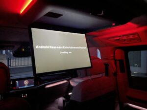 Ausgeklappter 17,5 Zoll Deckenmonitor im VW T7 Multivan beim Startvorgang mit roter Ambientebeleuchtung